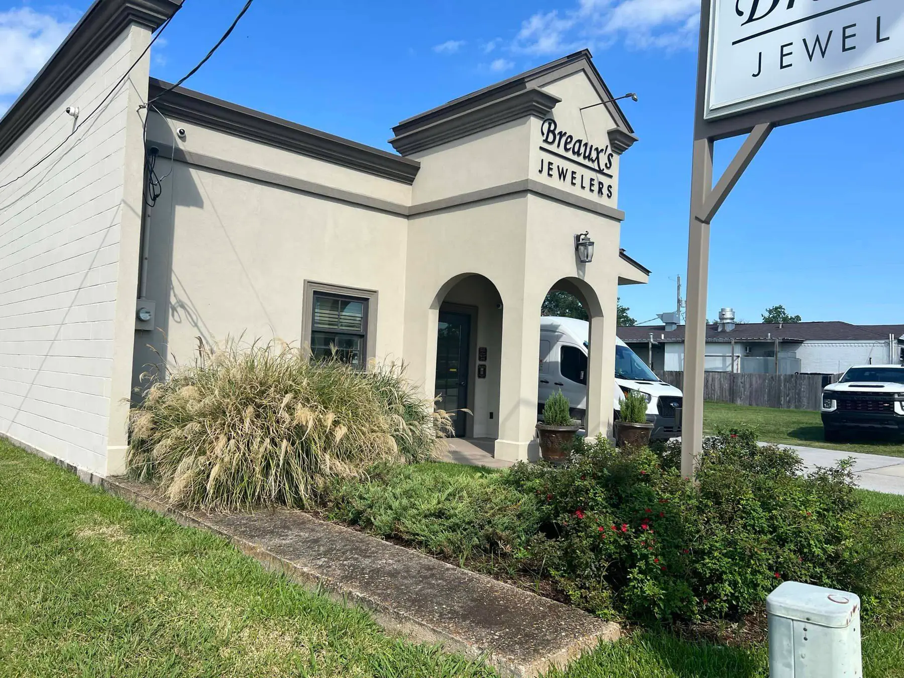 Overgrown grasses and shrubs in front of Breaux's Jewelers, awaiting a garden renovation.