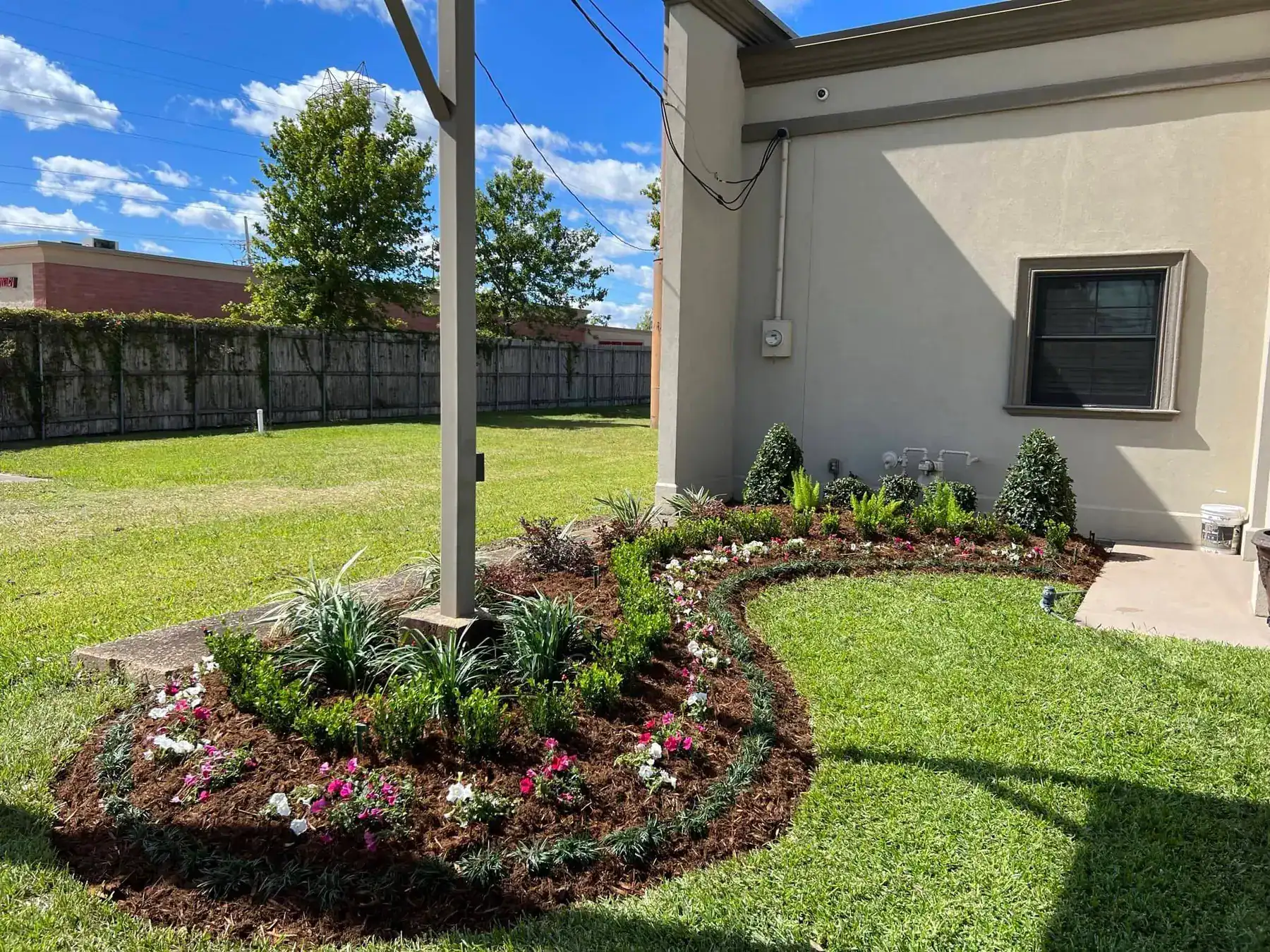 Elegantly redesigned garden with vibrant flowers and sculpted shrubs enhancing the entrance of Breaux's Jewelers.
