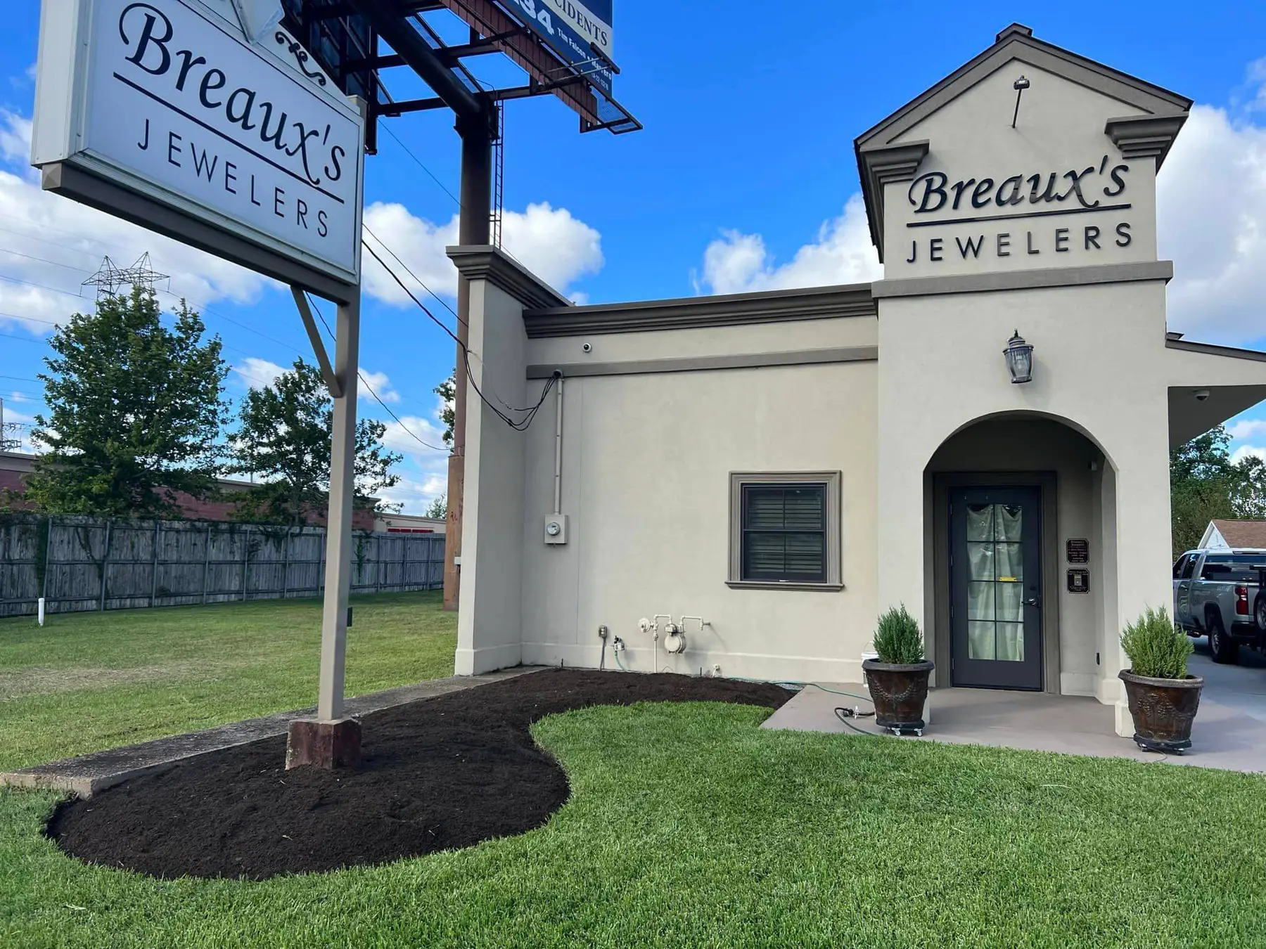 Freshly prepared soil bed ready for planting, framing the entrance of Breaux's Jewelers.