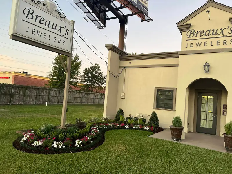 Elegantly redesigned garden with vibrant flowers and sculpted shrubs enhancing the entrance of Breaux's Jewelers.
