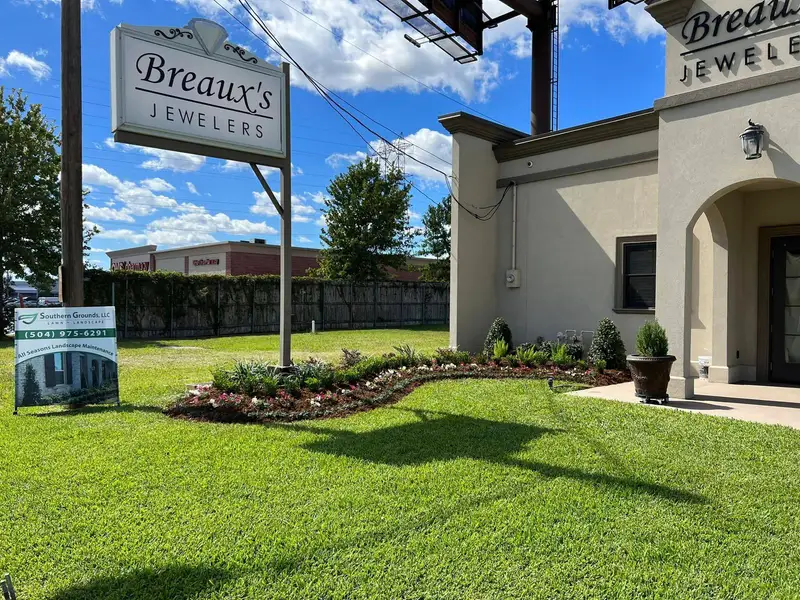 Elegantly redesigned garden with vibrant flowers and sculpted shrubs enhancing the entrance of Breaux's Jewelers.