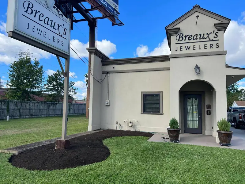 Freshly prepared soil bed ready for planting, framing the entrance of Breaux's Jewelers.