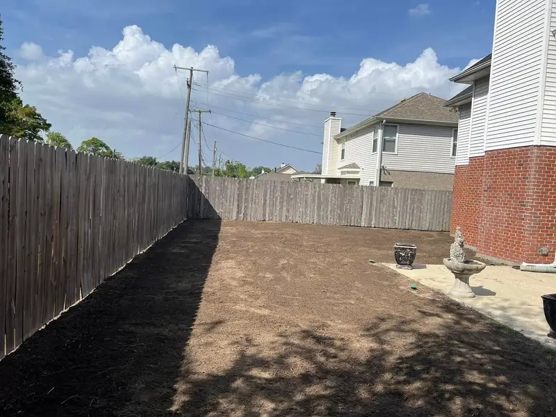 A residential backyard prepared for new sod installation, featuring bare soil ready for transformation, serviced by Southern Grounds LLC.