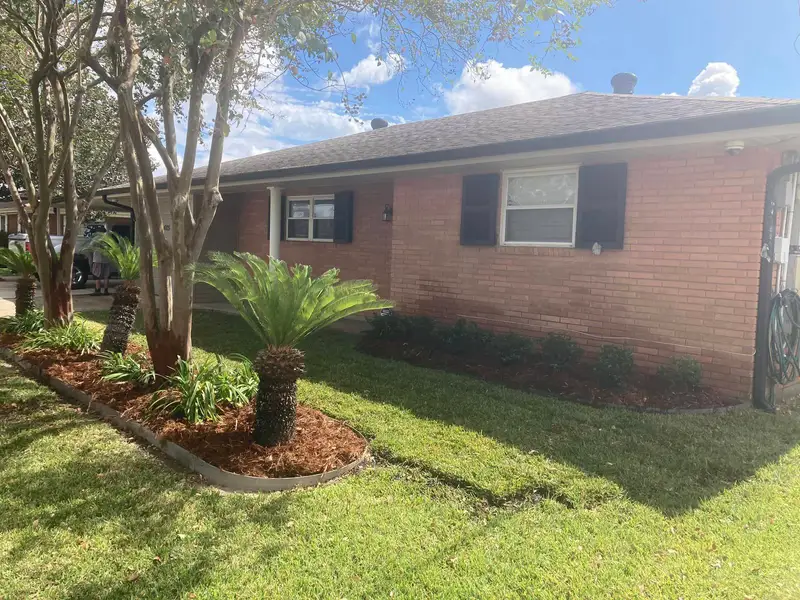 Professional landscaping services by Southern Grounds LLC featuring vibrant flower beds and neatly trimmed lawns in a New Orleans home.