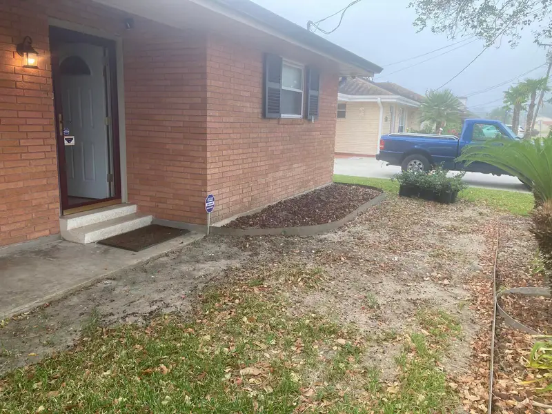 Professional landscaping services by Southern Grounds LLC featuring vibrant flower beds and neatly trimmed lawns in a New Orleans home.