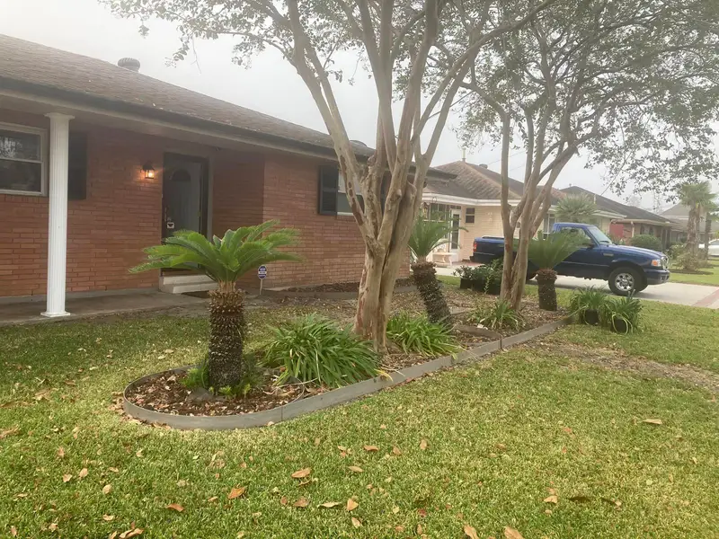 Professional landscaping services by Southern Grounds LLC featuring vibrant flower beds and neatly trimmed lawns in a New Orleans home.
