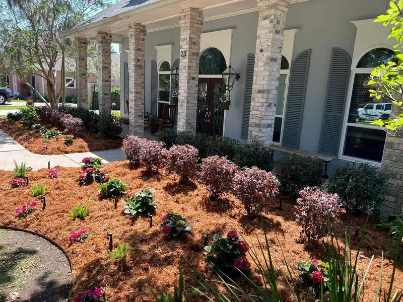 Professional landscaping services by Southern Grounds LLC featuring vibrant flower beds and neatly trimmed lawns in a New Orleans home.