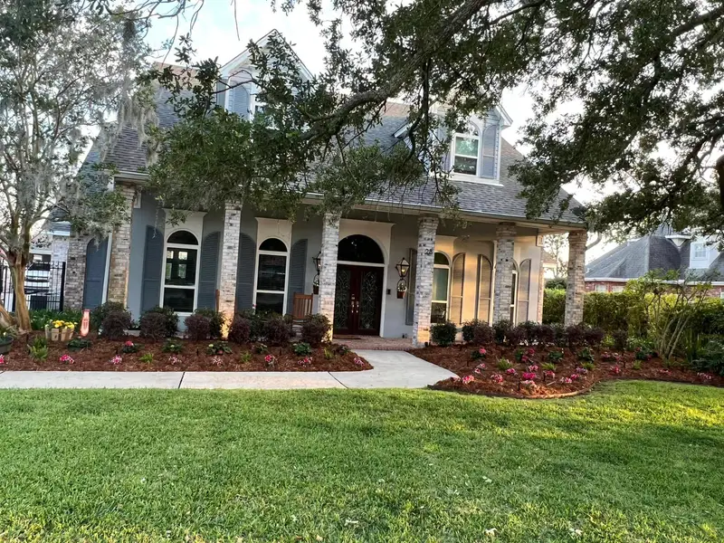 Professional landscaping services by Southern Grounds LLC featuring vibrant flower beds and neatly trimmed lawns in a New Orleans home.
