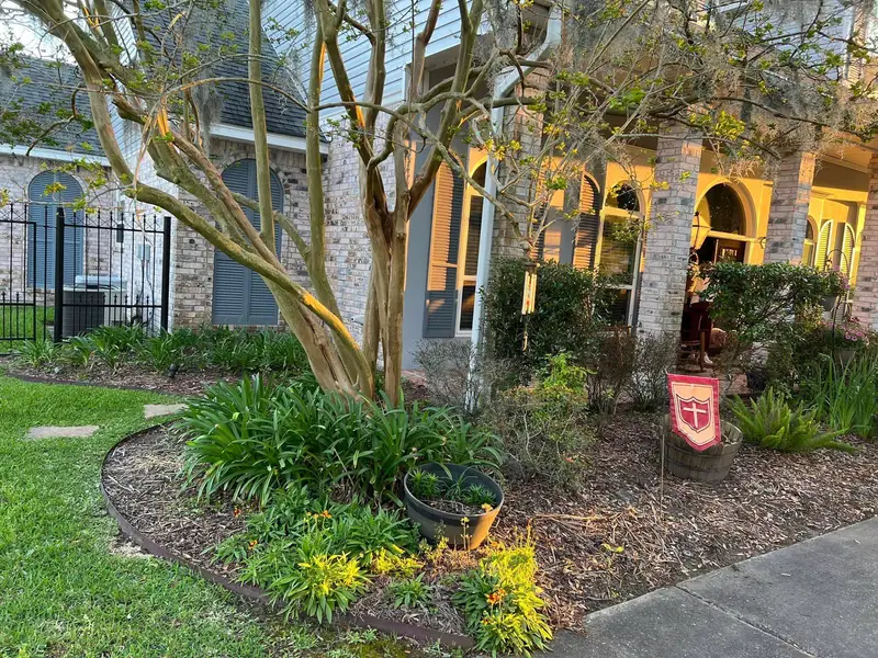 Professional landscaping services by Southern Grounds LLC featuring vibrant flower beds and neatly trimmed lawns in a New Orleans home.