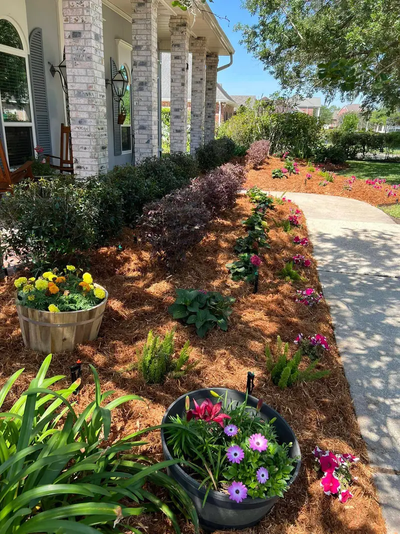 Professional landscaping services by Southern Grounds LLC featuring vibrant flower beds and neatly trimmed lawns in a New Orleans home.