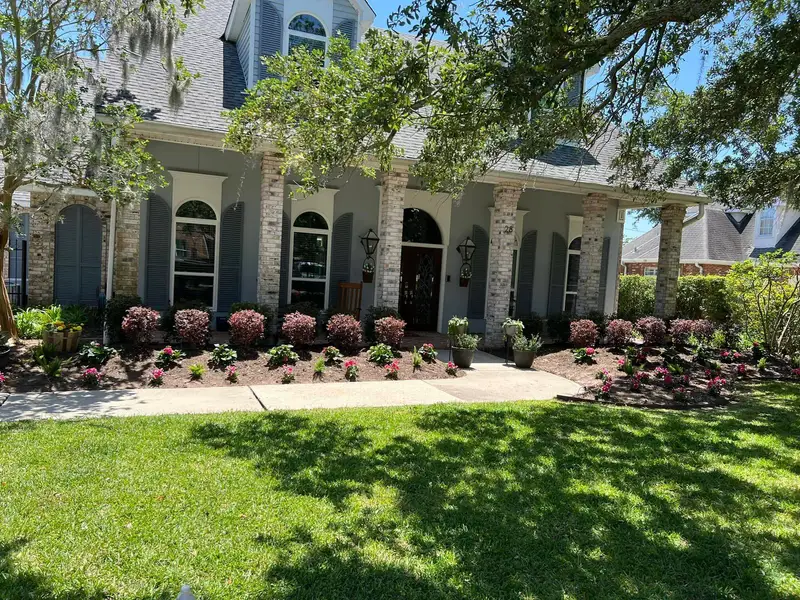 Professional landscaping services by Southern Grounds LLC featuring vibrant flower beds and neatly trimmed lawns in a New Orleans home.